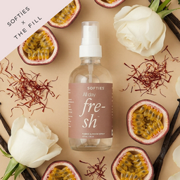 Softies x The Fill All Day Fresh™ Fabric & Room Spray Fabric and room spray bottle labeled 'SOFTIES All day fre-sh' surrounded by flowers and natural elements on a beige background.